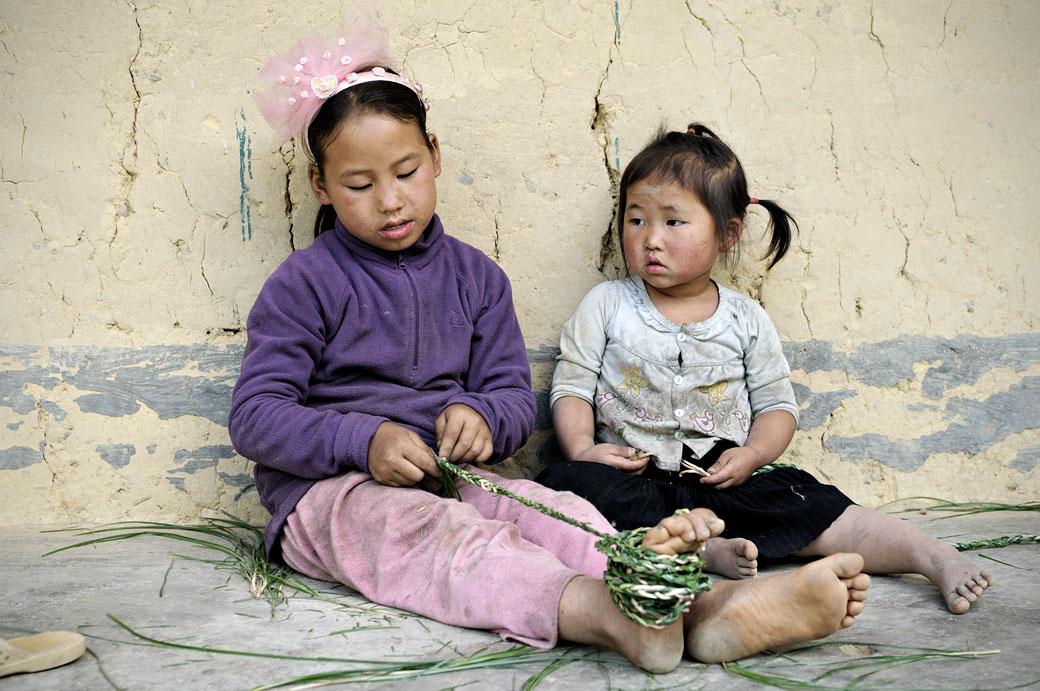 Petites filles assises contre le mur d'une maison, Vietnam