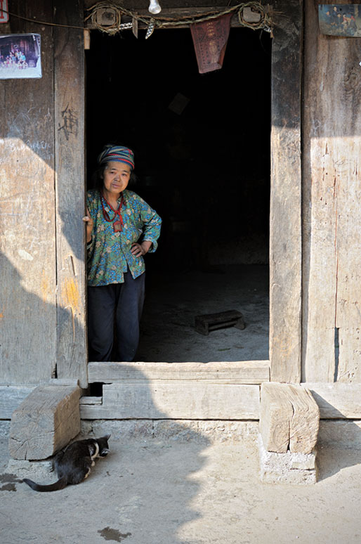 Femme Hmong à la porte d'une maison traditionnelle, Vietnam