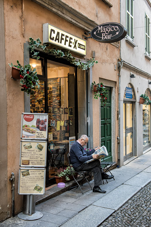 Homme qui lit son journal dans une rue de Pavie, Italie