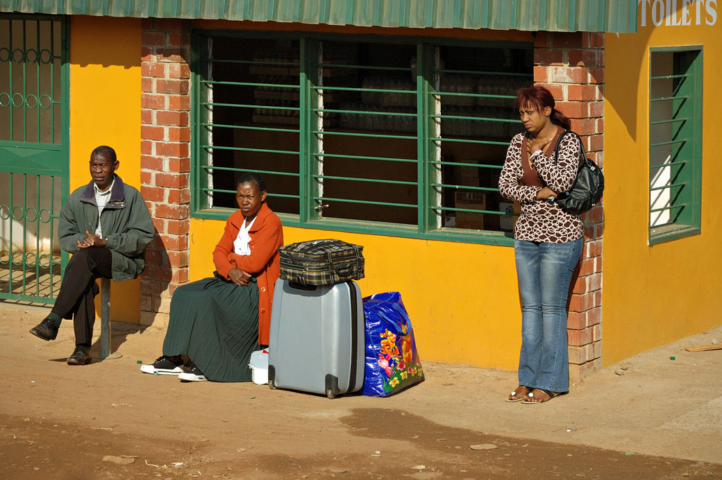 Trois personnes et des bagages à un arrêt de bus, Zambie