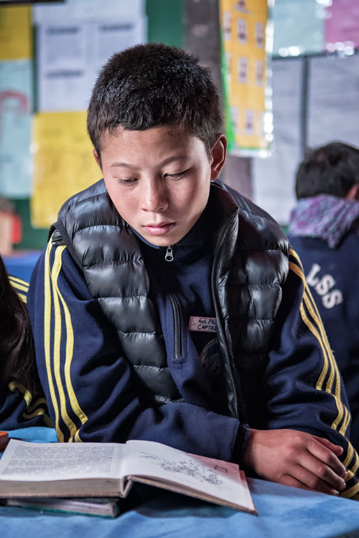 Garçon qui lit dans une classe d'école de Laya, Bhoutan