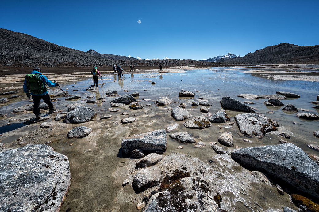 Trekkeurs qui traversent un plan d'eau en route pour Chukarpo, Bhoutan