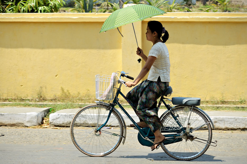 Jeune femme à vélo avec une ombrelle à Sittwe, Birmanie
