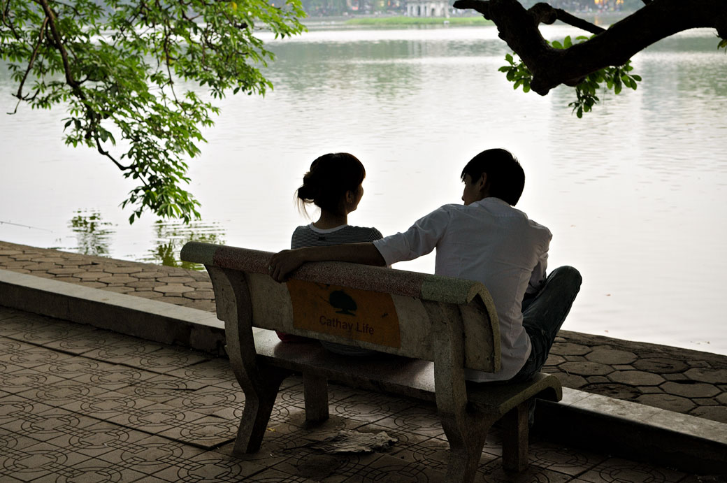 Jeune couple sur un banc au bord du lac Hoan Kiem à Hanoi, Vietnam