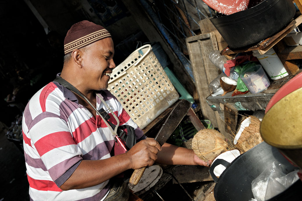 Homme qui casse une noix de coco au marché de Borobudur, Indonésie