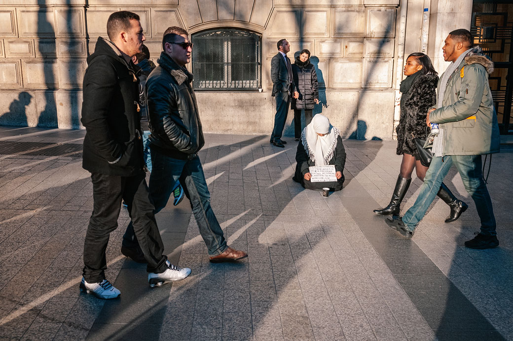 Mendiante et passants sur l'avenue des Champs-Élysées à Paris