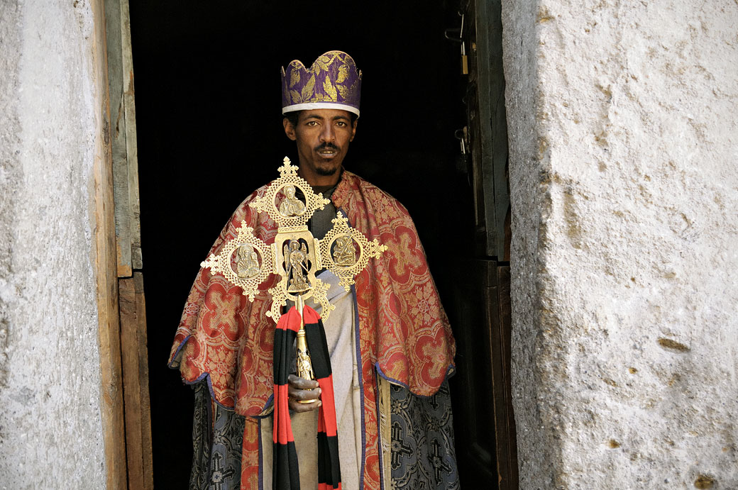 Prêtre tenant une croix orthodoxe à la porte de l'église Asheten-Mariam, Ethiopie