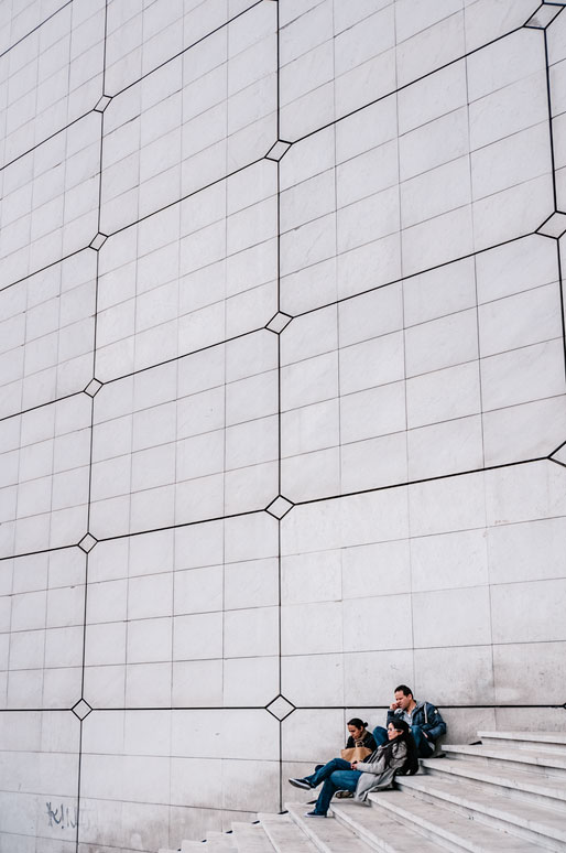 Trois personnes sur les escaliers de la Grande Arche de la Défense