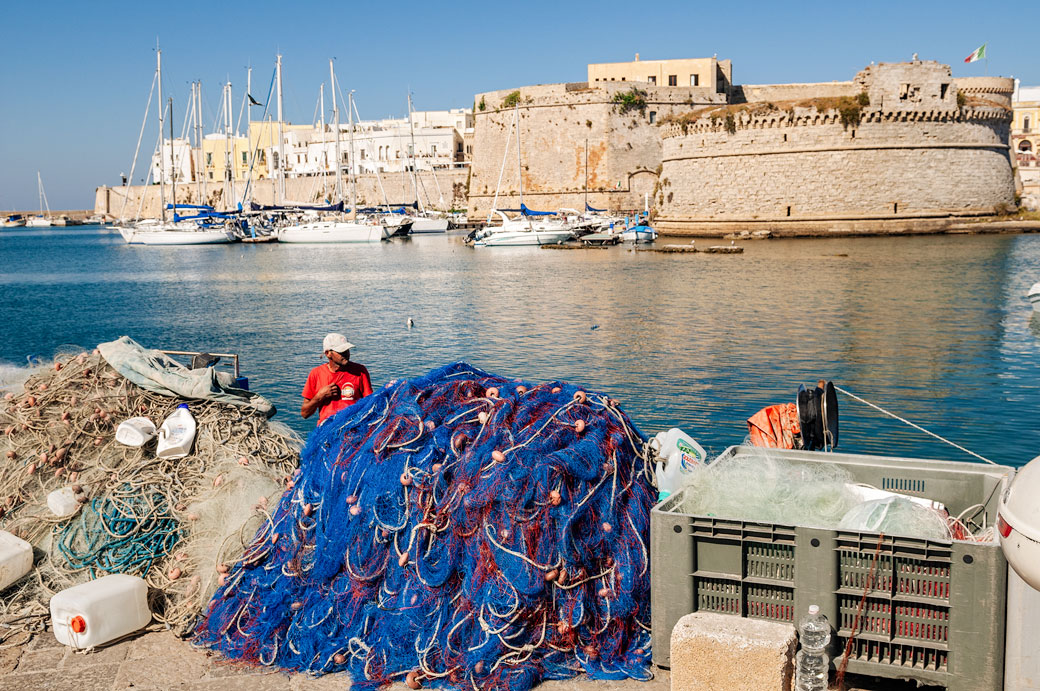Filets de pêche et pêcheur sur un quai de Gallipoli, les Pouilles