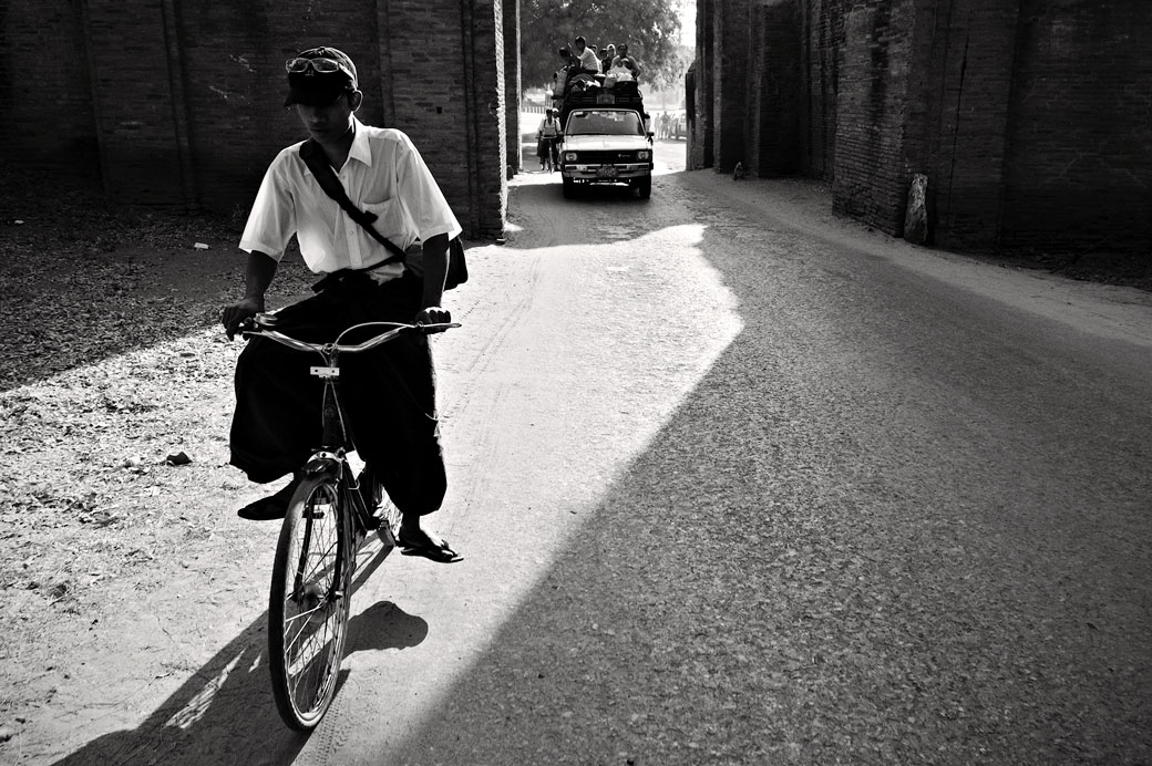 Un cycliste et un minibus bien chargé à Bagan, Birmanie