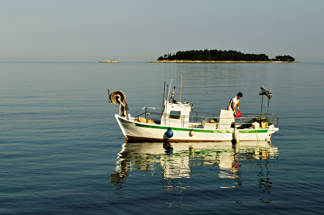 Pêcheur sur un bateau blanc au large de Rovinj, Croatie