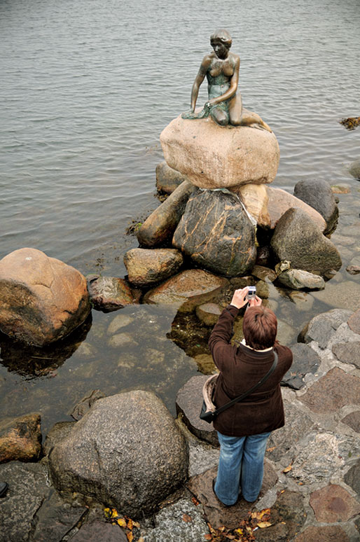 Une femme photographie la statue de la Petite Sirène à Copenhague