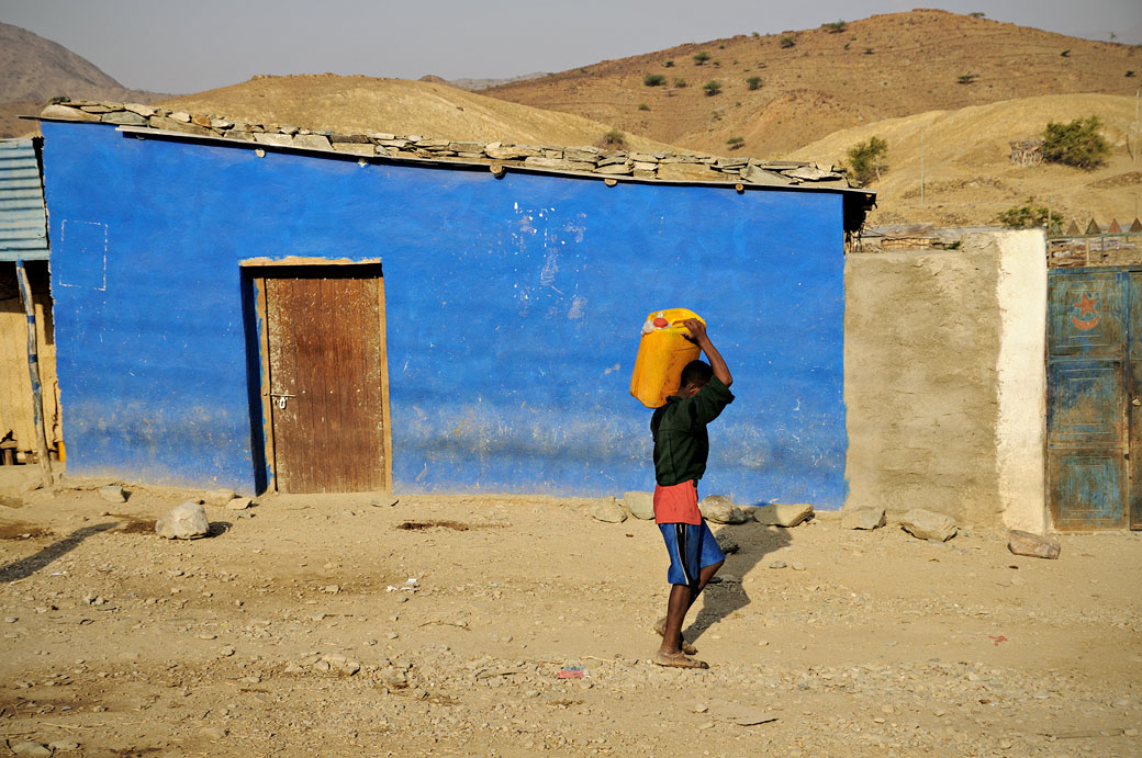 Passant devant une maison bleu dans une rue de Berahle, Ethiopie