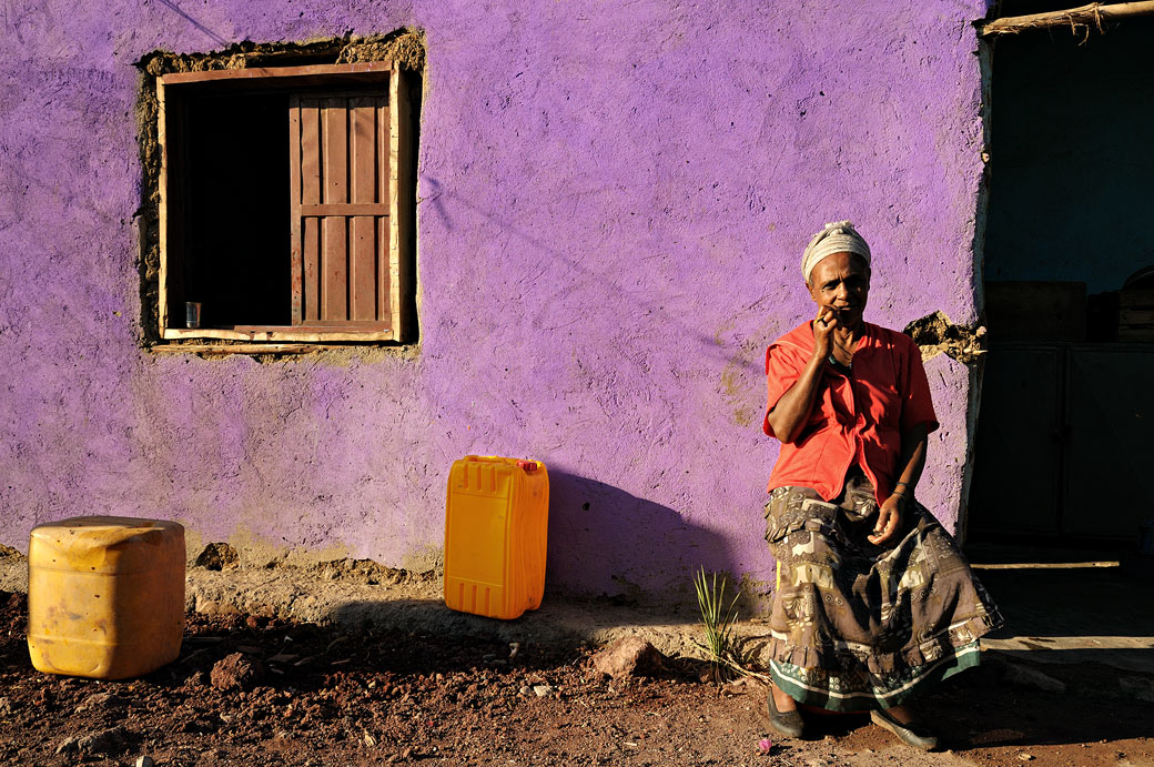 Femme devant sa maison au mur violet, Ethiopie