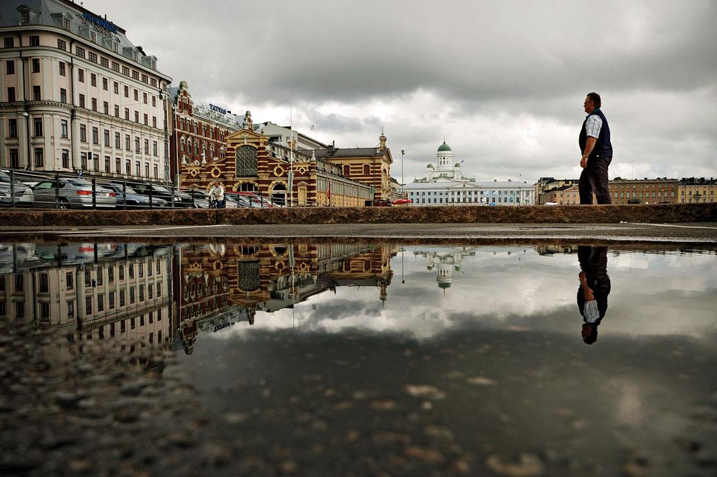 Reflet d'un passant et de la cathédrale dans une flaque d'eau, Helsinki