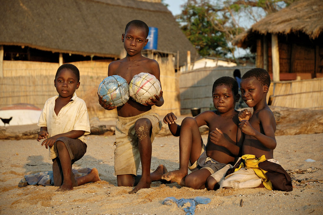 Enfants avec des ballons de foot locaux sur la plage à Cape Maclear