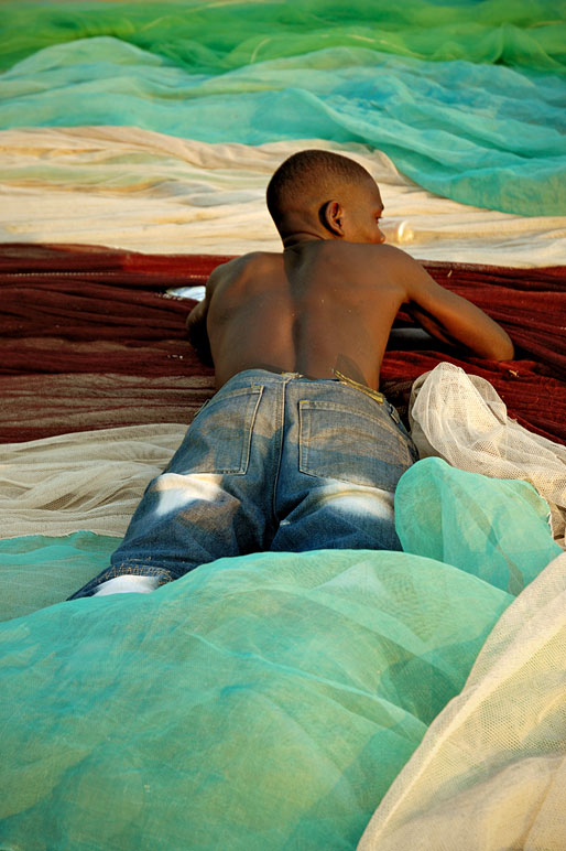 Pêcheur couché sur un filet de pêche coloré à Cape Maclear, Malawi