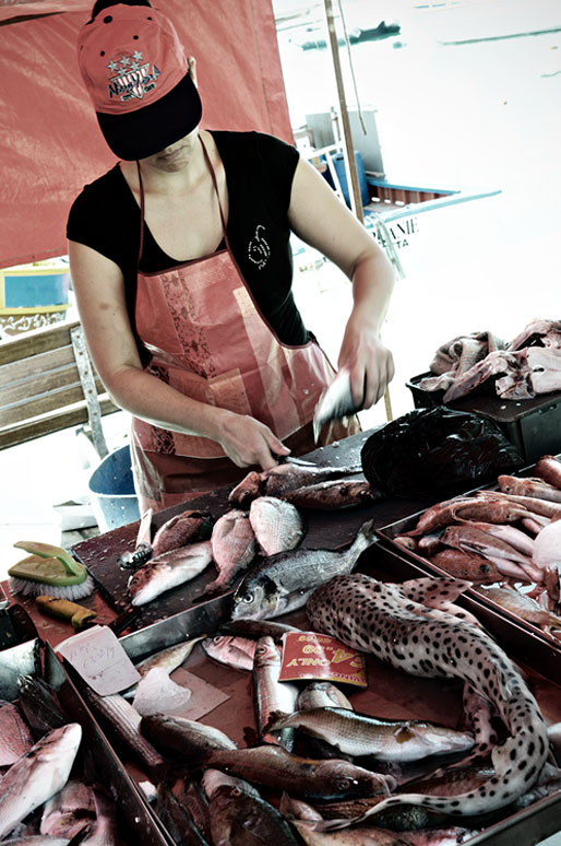 Femme qui découpe des poissons au marché de Marsaxlokk, Malte