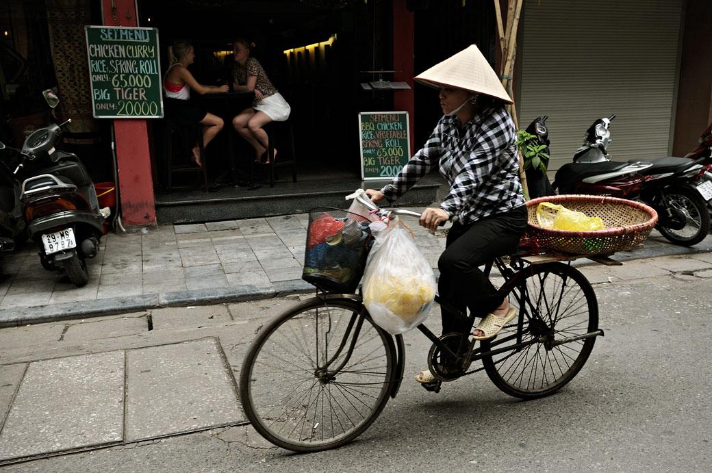 Femme sur un vélo et touristes à Hanoi, Vietnam