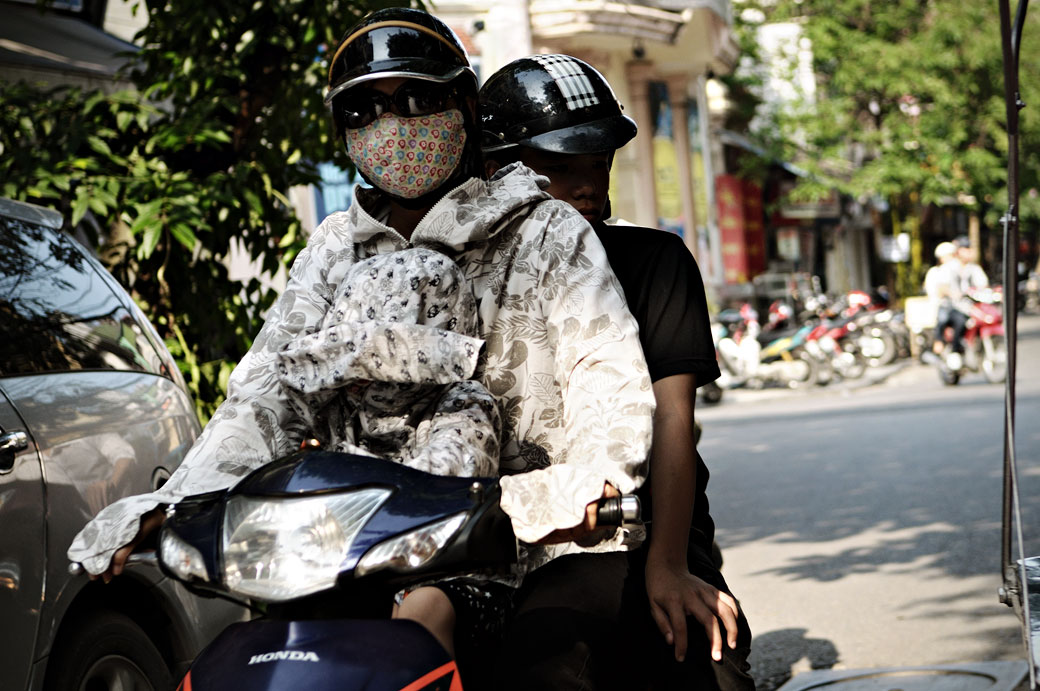 Femme avec un masque sur un scooter à Hanoi, Vietnam