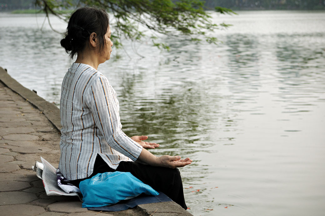 Femme qui médite au bord du lac Hoan Kiem à Hanoi, Vietnam