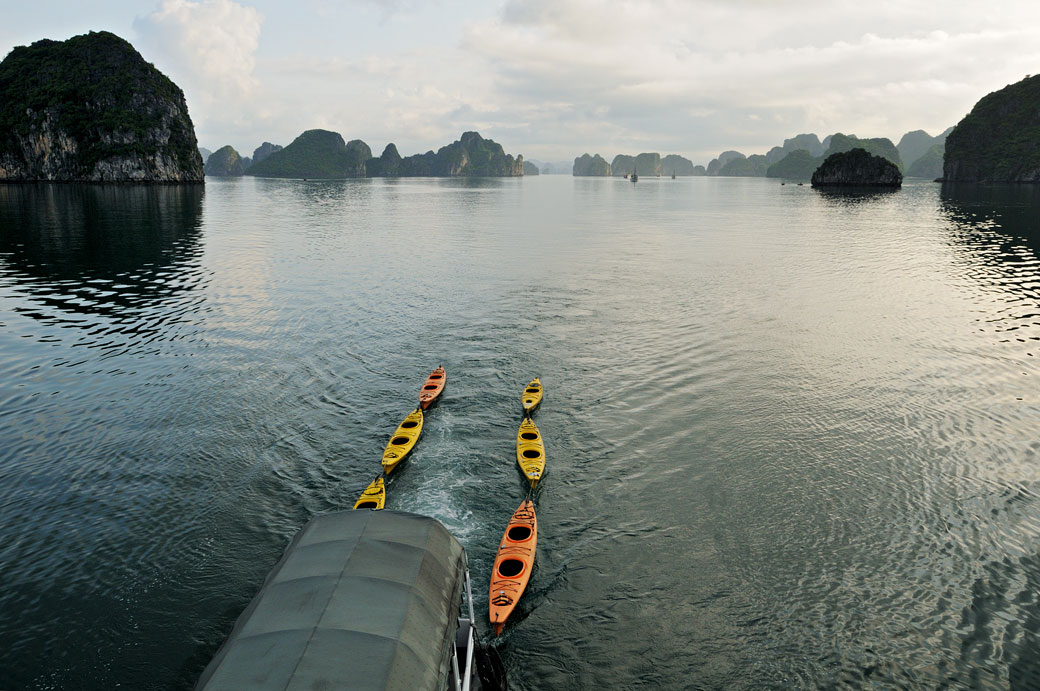 Bateau tirant des kayaks dans la baie d'Halong, Vietnam